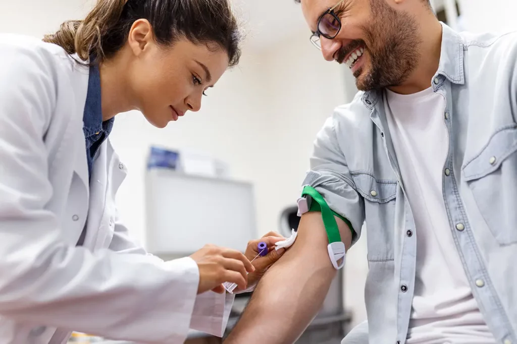 female phlebotomy technician getting male patient ready for blood drawing