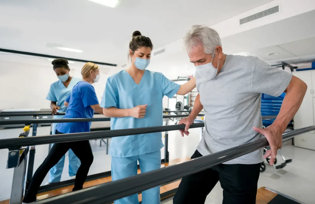 Physical Therapy Aide with individual using aide bars to walk.